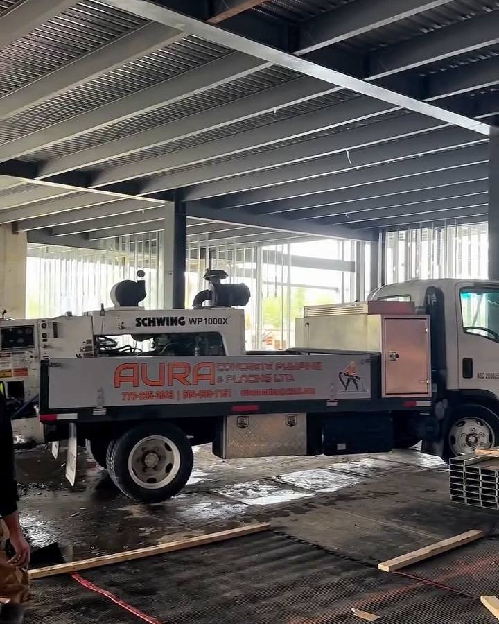 Aura concrete pump truck parked under a new steel-framed building in Vancouver, ready for a 125 cubic metre slab pour